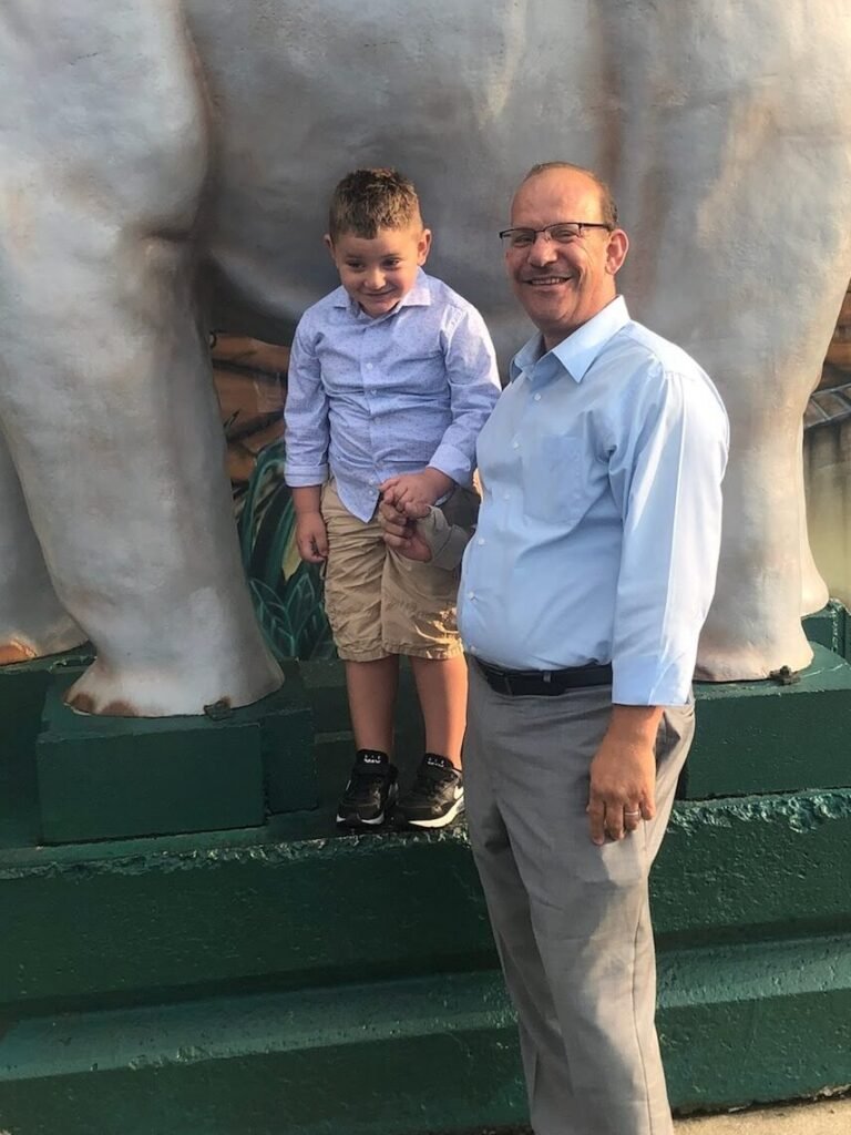 Jamal Abudan smiling and holding hands with a young boy, symbolizing community engagement and peace-building efforts